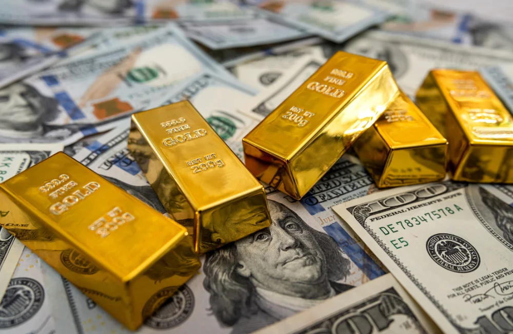 แท่งทองคำ "999.9 FINE GOLD" "NET WT 200g" หลายแท่งวางอยู่บนธนบัตรดอลลาร์สหรัฐ "FEDERAL RESERVE NOTE" "ONE HUNDRED DOLLARS" "DE 78347578 A" "E5" ที่กระจัดกระจาย